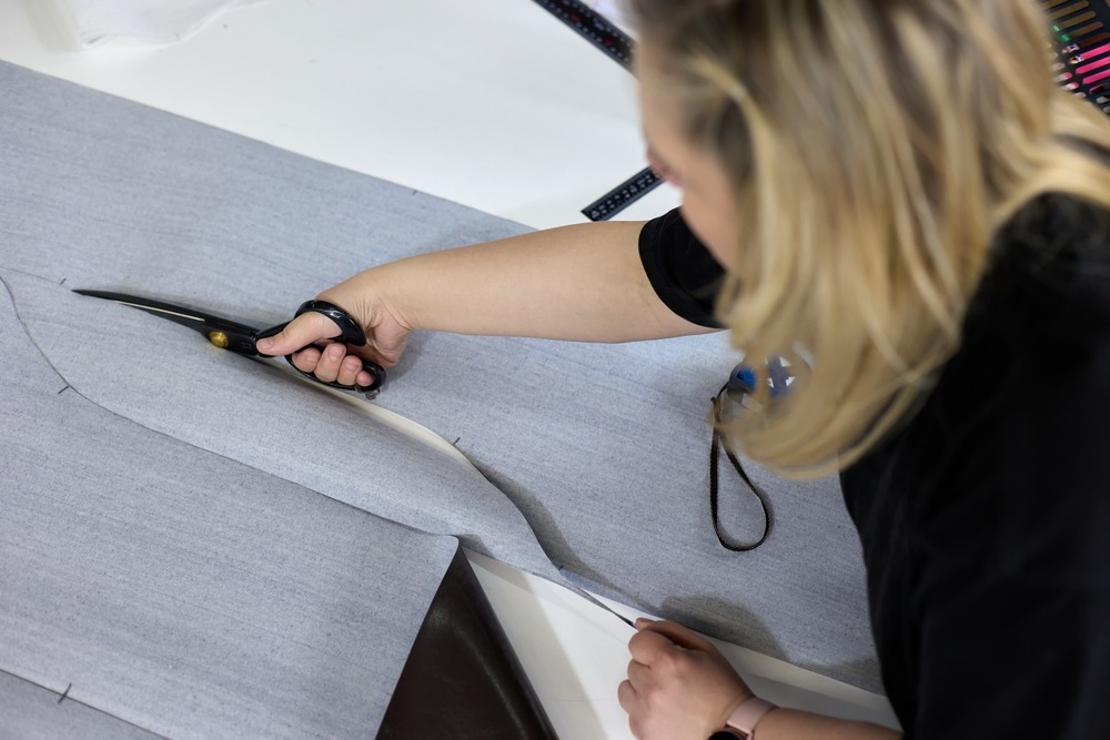 a woman cutting piece of cloth using scissor